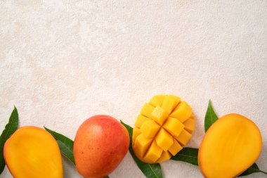 Taze dilimlenmiş, kesilmiş, dilimlenmiş, olgun mango gri masa zemininde yemek için yaprak ile birlikte..