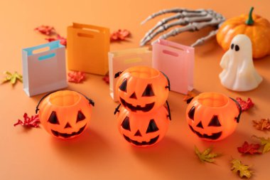 Alışveriş arabası, akçaağaç yaprakları ve turuncu masa zemininde balkabağı olan Cadılar Bayramı sonbahar alışveriş tasarımı konsepti.