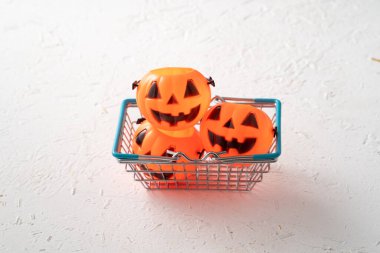 Cadılar Bayramı sonbahar alışveriş konsepti alışveriş arabası ve beyaz masa arkaplanlı balkabağı.