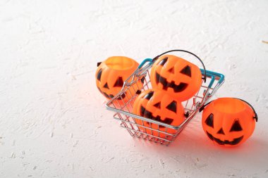 Cadılar Bayramı sonbahar alışveriş konsepti alışveriş arabası ve beyaz masa arkaplanlı balkabağı.