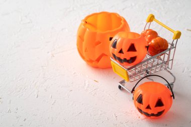 Cadılar Bayramı sonbahar alışveriş konsepti alışveriş arabası ve beyaz masa arkaplanlı balkabağı.