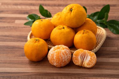 Ahşap masa arkasındaki tabakta taze mandalina portakalı..