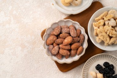 Beyaz masa arkasındaki kâselerde aromalı fındıklar..