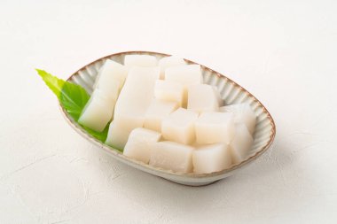 Japonya 'da Konnyaku olarak da adlandırılan beyaz masa arka planındaki bir tabakta kare şeklinde ham konjac.