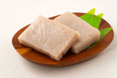 Japonya 'da Konnyaku olarak da adlandırılan beyaz masa arka planındaki bir tabakta kare şeklinde ham konjac.