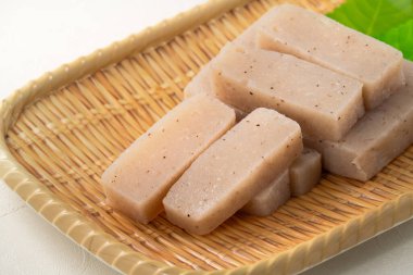 Japonya 'da Konnyaku olarak da adlandırılan beyaz masa arka planındaki bir tabakta kare şeklinde ham konjac.