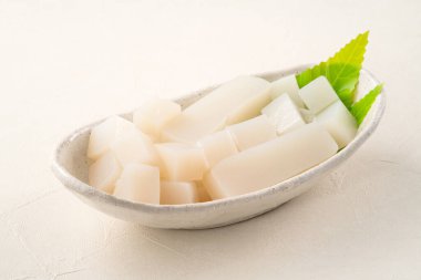 Japonya 'da Konnyaku olarak da adlandırılan beyaz masa arka planındaki bir tabakta kare şeklinde ham konjac.