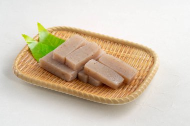 Japonya 'da Konnyaku olarak da adlandırılan beyaz masa arka planındaki bir tabakta kare şeklinde ham konjac.