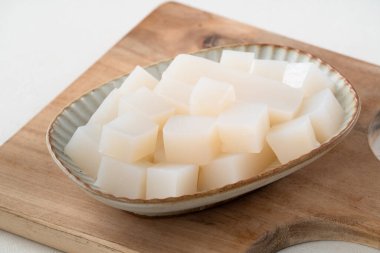 Japonya 'da Konnyaku olarak da adlandırılan beyaz masa arka planındaki bir tabakta kare şeklinde ham konjac.