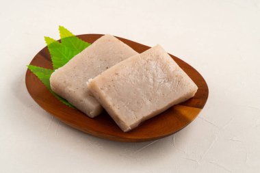 Japonya 'da Konnyaku olarak da adlandırılan beyaz masa arka planındaki bir tabakta kare şeklinde ham konjac.