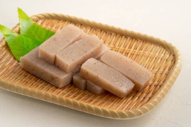 Japonya 'da Konnyaku olarak da adlandırılan beyaz masa arka planındaki bir tabakta kare şeklinde ham konjac.