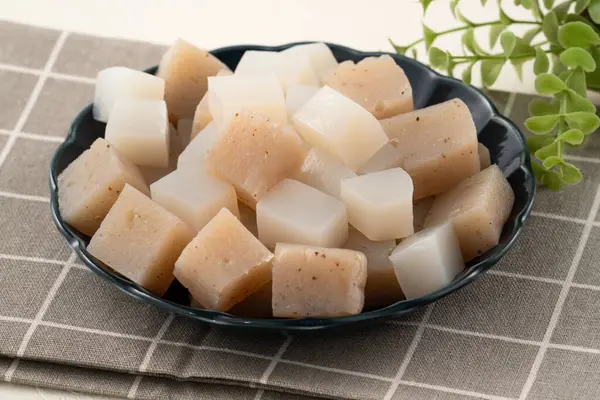 Japonya 'da Konnyaku olarak da adlandırılan beyaz masa arka planındaki bir tabakta kare şeklinde ham konjac.