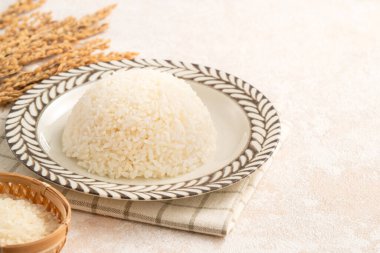 Bir kase taze pişmiş beyaz pirinç, yumuşak, kabarık ve beyaz masa arkasında hafifçe parıltılı..