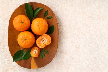 Beyaz masa arkaplanındaki tabakta taze mandalina portakalı..