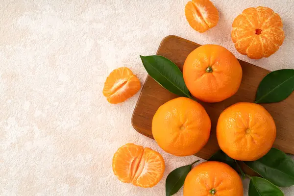 Beyaz masa arkaplanındaki tabakta taze mandalina portakalı..