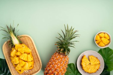 Arkaplanda tropik yapraklar olan yarım bir ananas kasesine yerleştirilmiş sulu ananas parçaları..