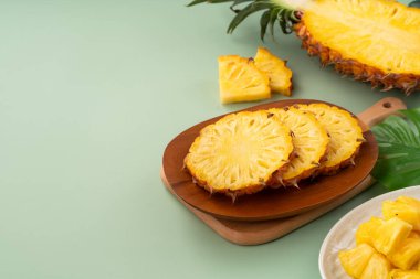 Arkaplanda tropik yapraklar olan yarım bir ananas kasesine yerleştirilmiş sulu ananas parçaları..