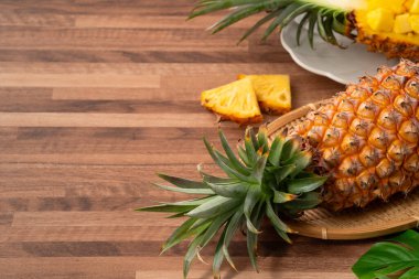 Arkaplanda tropik yapraklar olan yarım bir ananas kasesine yerleştirilmiş sulu ananas parçaları..