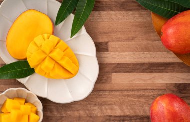 Ahşap bir masa üzerinde mangoları olan sulu sarı mango küpleri
