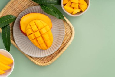 Sulu sarı mango küpleri ve yeşil masa arkaplanı.