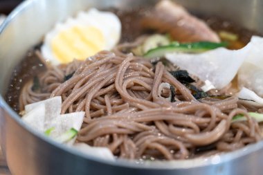 Soğutulmuş sebze ve haşlanmış yumurtayla servis edilen soğuk Kore eriştelerini tazeliyorum..