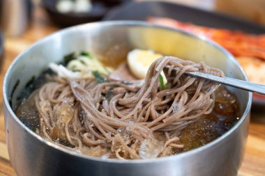 Soğutulmuş sebze ve haşlanmış yumurtayla servis edilen soğuk Kore eriştelerini tazeliyorum..