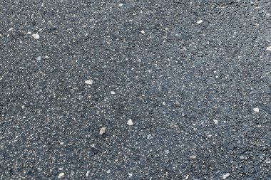 Details of the textured asphalt road background which is made of asphalt and small stones. clipart