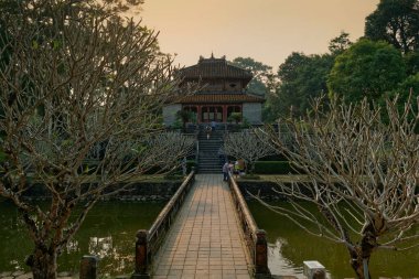 Hue, Vietnam - 21 Mart 2023: Minh Mang Mezarı 'ndaki Minh Lau Pavyonu' nun önünde bir gelin, gölet, ağaçlar ve bazı turistler pavyonun önünde.