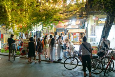 Hoi An, Vietnam - 22 Mart 2023: Bir grup Vietnamlı ve turist gece-gündüz dükkanın önünde meyve suyu ve meyve püresi bekliyorlar.