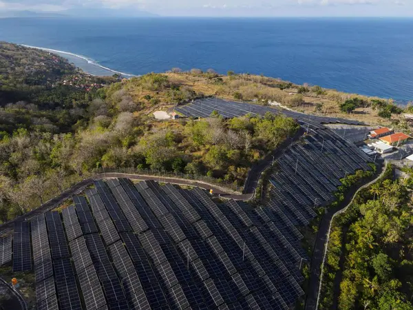 Nusa Penida, 28 Ağustos 2024: Güneş ışığından istifade eden güneş panelleri olan bir kıyı yamacı güneş çiftliği. Kurulum doğayla harmanlanarak, sakin ve doğal bir kümede sürdürülebilir enerjiyi temsil eder.