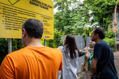 Bali, 25 Kasım 2022: Uluslararası katılımcılar deprem simülasyon eğitimi için Bali 'nin Benoa kentinde bir afet riski azaltma saha ziyareti sırasında tsunami tehlike bölgesi işareti gözlemlediler