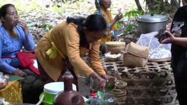 Bali, 15 Ekim 2023: Kadınlar ve turistler bambu masaları ve sepetleriyle canlı Penglipuran pazarında geleneksel abur cubur ve içeceklerin keyfini çıkarıyorlar