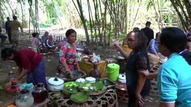 Bali, 15 Ekim 2023: Geleneksel gıda ve el sanatlarıyla dolu bambu masaları etrafında gezinen yerli halk ve ziyaretçilerle dolu açık hava Penglipuran pazarı