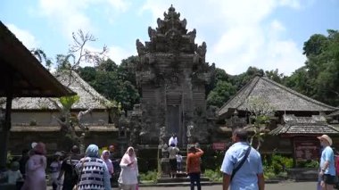 Bali, 15 Ekim 2023: Turistler Bali 'nin Penglipuran Köyü' nde taş oymalar ve yemyeşil alanlarla geleneksel bir Bali tapınağını keşfettiler