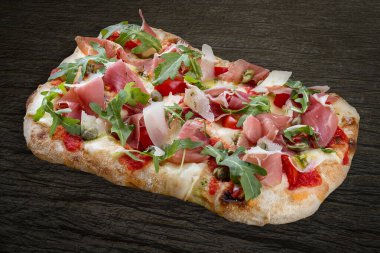 Prosciutto, roka, kapari, pelati soslu Sorrentina pizzası, pesto. Ahşap arka planda Roma pizzası dikdörtgeni