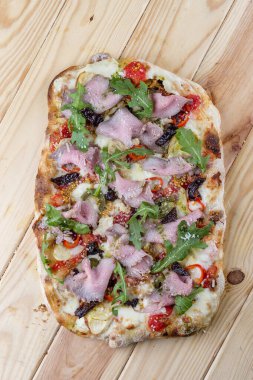 Biftekli pizza, enginar, biber, mozzarella, pesto. Ahşap arka planda Roma pizzası dikdörtgeni