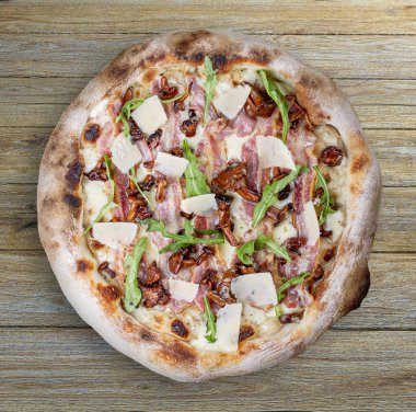 Pastırmalı, reçelli, roka, mozzarella, parmesan soslu pizza. Ahşap arka planda Napolili yuvarlak pizza.