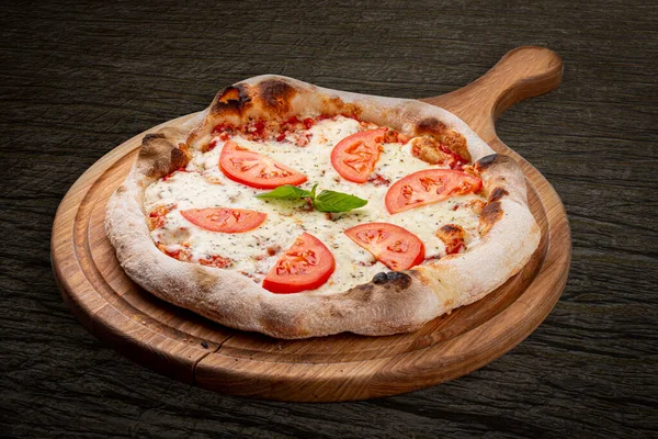 Pizza Margarita with tomato, mozzarella, pesto sauce, basil. Neapolitan round pizza on dark background
