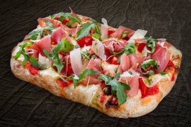 Prosciutto, roka, kapari, pelati soslu Sorrentina pizzası, pesto. Ahşap arka planda Roma pizzası dikdörtgeni