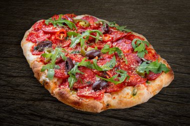 Chorizo, roka, jalapeno, chili, kalamata, pesto soslu pizza. Ahşap arka planda Roma pizzası dikdörtgeni