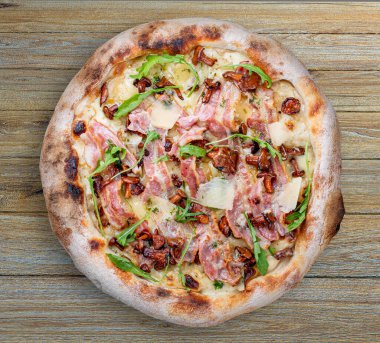 Pastırmalı, reçelli, roka, mozzarella, parmesan soslu pizza. Ahşap arka planda Napolili yuvarlak pizza.