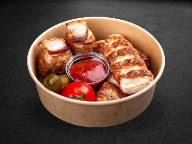 Fırında patates ve turşulu tavuk kebabı. Paketin içinde. Karanlık bir arka planda izole edilmiş.