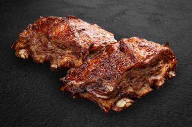 Izgara domuz kaburgası, el yapımı koyu taştan bir arka plan. Barbekü menüsü