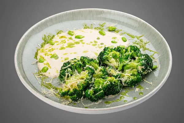 Krema soslu ve parmesanlı buğulanmış brokoli. Beyaz bir arkaplanda izole edilmiş. 