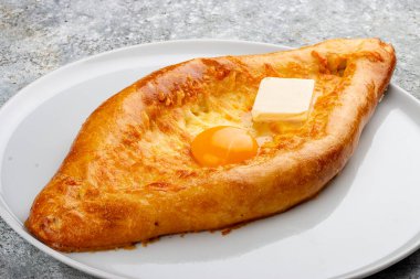 Peynirli, yumurtalı ve tereyağlı Adjar tarzı khachapuri. Kafkas mutfağı. Gri arkaplandaki izole görüntü.