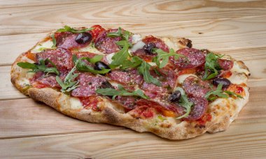 Chorizo, roka, jalapeno, chili, kalamata, pesto soslu pizza. Ahşap arka planda Roma pizzası dikdörtgeni