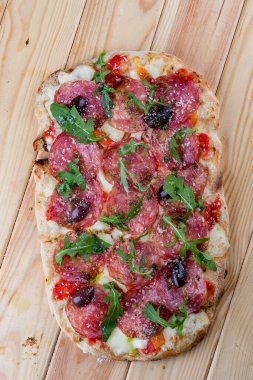 Chorizo, roka, jalapeno, chili, kalamata, pesto soslu pizza. Ahşap arka planda Roma pizzası dikdörtgeni
