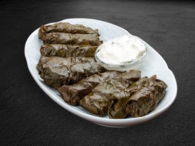 Kuzu eti ve beyaz soslu Dolma. Kıymalı üzüm yaprakları. Doğu mutfağı. Karanlık bir arka planda izole edilmiş.