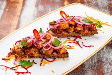 Dana beyinli ve soğanlı çavdar ekmeği. Ahşap bir arka planda.