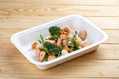 Pişmiş somon ve sebze. Sağlıklı beslenme. Paket yemek. Çevre ambalajı. Ahşap bir arka planda.